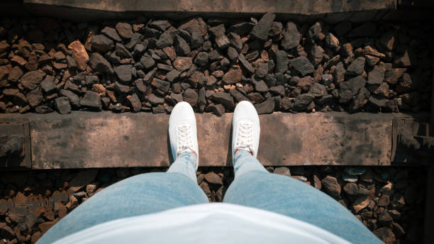 istock Women's feet in sneakers on the rails. 1278562789