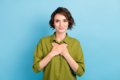 Photo of lovely lady short hairstyle, hands chest smile peaceful rest comfortable cozy spring wear green shirt isolated blue color background