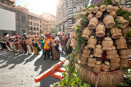 Florence, Italy - 2020, September 26:
Old wagon full of Chianti wine flasks, called Carro Matto, in front of the Baptistery of San Giovanni, during the historical reenactment ”Bacco Artigiano 2020 Festival”.