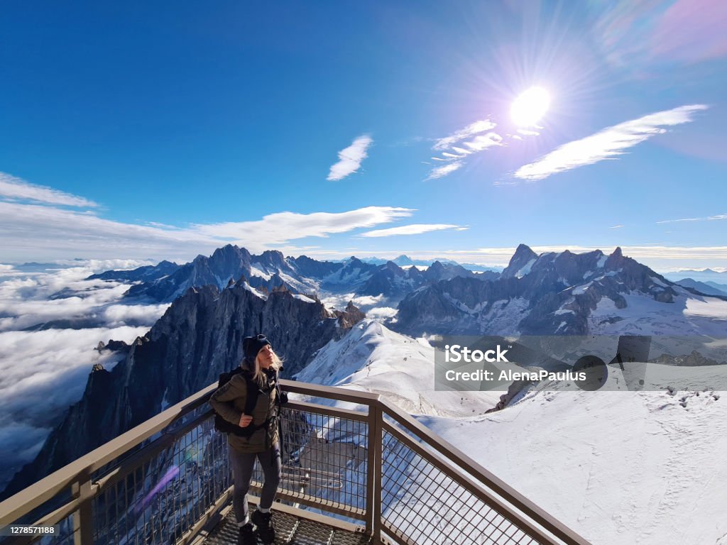 Woman looking at view from Aiguille du Midi. Chamonix needles, Mont Blanc, Haute-Savoie, Alps, France Woman looking at view from the Aiguille du Midi. The Aiguille du Midi is a 3,842-metre-tall mountain in the Mont Blanc massif within the French Alps. It is a popular tourist destination and can be directly accessed by cable car from Chamonix that takes visitors close to Mont Blanc.Chamonix needles, Mont Blanc, Haute-Savoie, Alps, France French Alps Stock Photo