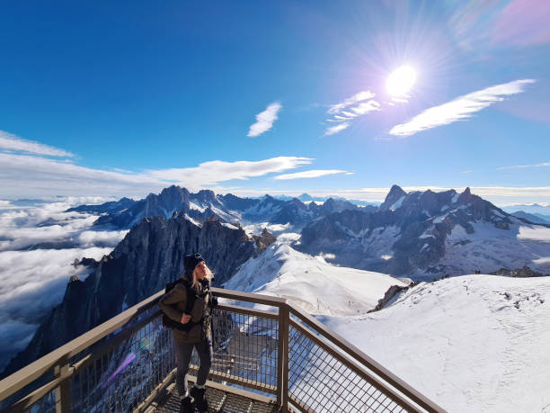 Woman looking at view from Aiguille du Midi. Chamonix needles, Mont Blanc, Haute-Savoie, Alps, France Woman looking at view from the Aiguille du Midi. The Aiguille du Midi is a 3,842-metre-tall mountain in the Mont Blanc massif within the French Alps. It is a popular tourist destination and can be directly accessed by cable car from Chamonix that takes visitors close to Mont Blanc.Chamonix needles, Mont Blanc, Haute-Savoie, Alps, France aiguille de midi photos stock pictures, royalty-free photos & images