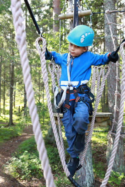 istock Kid overcoming hanging ropes obstacle in adventure park 1278572191