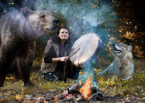 Shaman woman plays a tambourine among wild animals