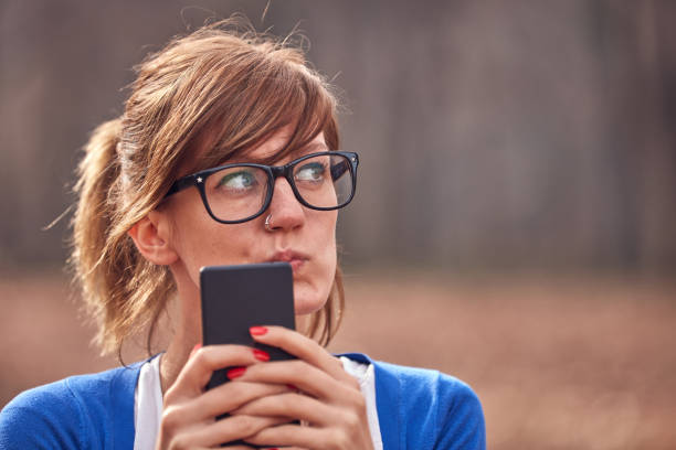 istock Young woman using smartphone in autumn colored park. 1278577053