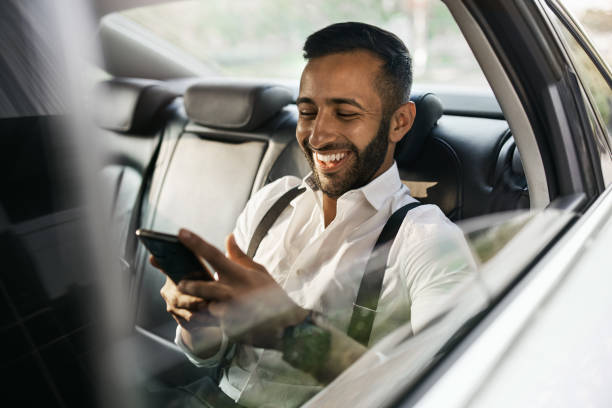 bearded indian muslim businessman using smart phone shot through taxi car window - india car people business imagens e fotografias de stock