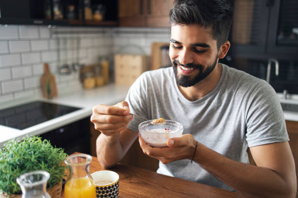istock Attractive bearded man sitting at his nice kitchen table, eating cereals for breakfast 1278583793