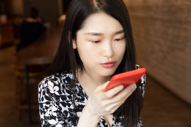 istock Chinese woman using an red smart phone in coffee shop 1278588302