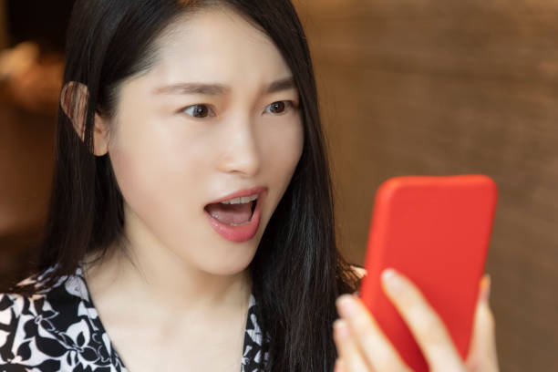 istock Chinese woman using an red smart phone in coffee shop 1278588400