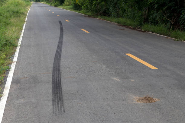Traces of black tire brakes on the road. Close-up of black traces of tires, since the brake is the only long wheel on the road in rural Thailand. street skid marks stock pictures, royalty-free photos & images