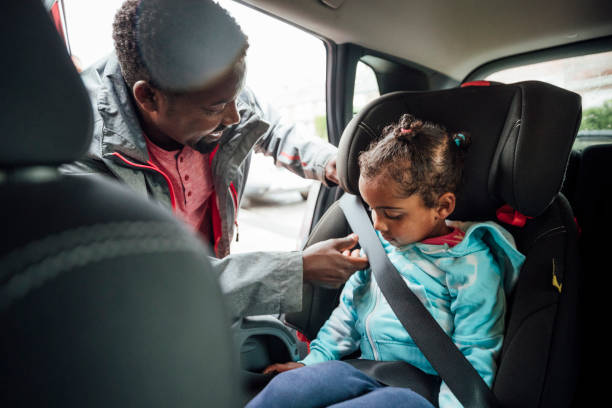 Making Sure It's Safe Father buckling his young daughter into a car seat. They are going on a road trip together. Taken during the Covid 19 pandemic. fastening photos stock pictures, royalty-free photos & images