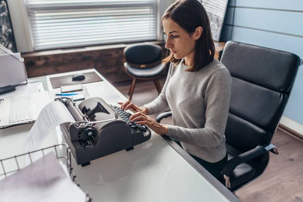 istock Woman in office at her desk typing on a typewriter 1278592110