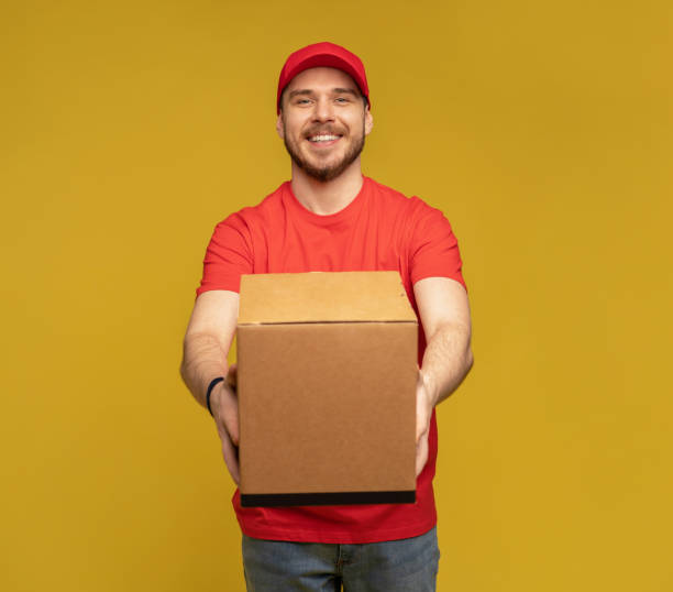 istock Delivery man with box in studio isolated on yellow background. 1278592653