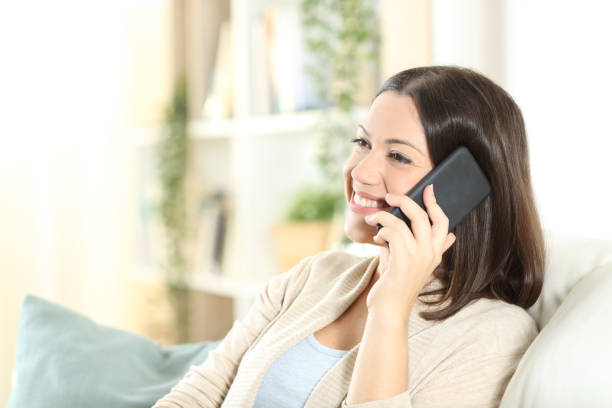 istock Happy woman talking on phone on a sofa at home 1278595510