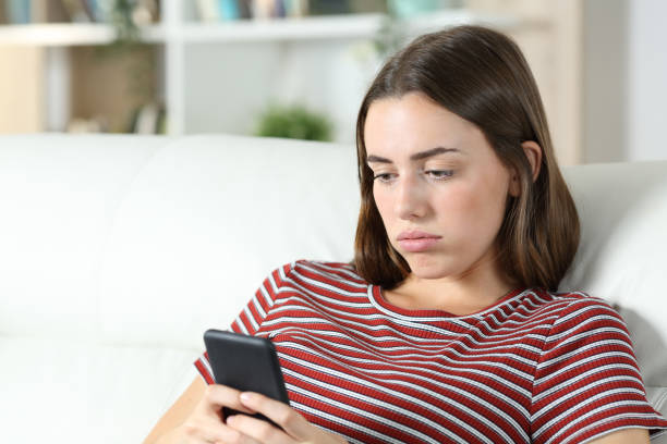 istock Bored teen checking smart phone on a sofa 1278595531