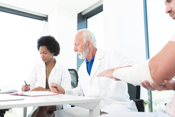 istock Doctor studying arm injury of patient & assistant writing notes 1278596915