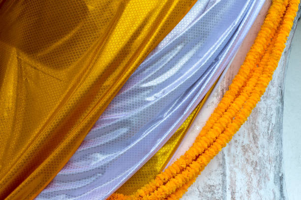 Background image, close-up surface, yellow patterned fabric overlapping with white cover, buddha and hanging garland.