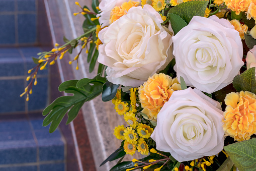 Close-up view of white and yellow fake rose bouquets decorating beautifully in the staircase.