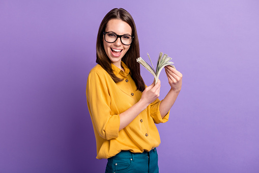 Photo of lovely young girl look up empty space toothy smile wear eyewear yellow shirt isolated purple color background