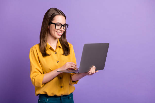 foto von schönen jungen mädchen halten pc aussehen bildschirm tragen brille gelb shirt isoliert violett farbe hintergrund - netbook stock-fotos und bilder