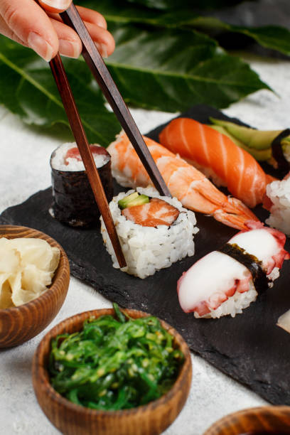 istock Close up of hand taking roll with chopsticks from a plate 1278599098