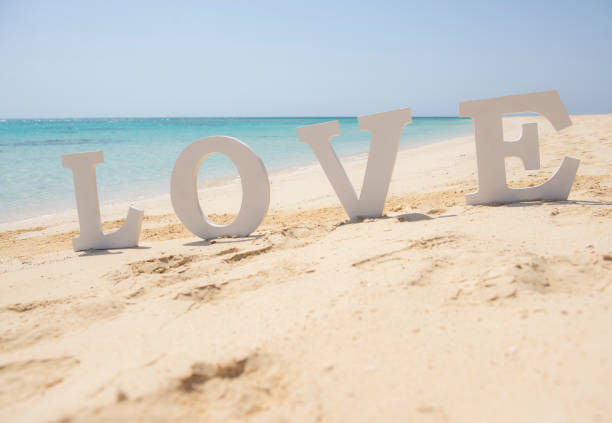 Closeup of romantic love sign on tropical island sandy beach paradise with ocean in background