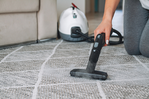 Woman cleaning the carpet with a steam cleaner