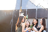 ポートの若いかわいいアジアの女の子は屋上レストランでパーティーを持つ親友をギャング。ビールアルコールを飲む女の子と幸せな感じのトーストボトルは、笑顔で楽しい、楽しいです。�