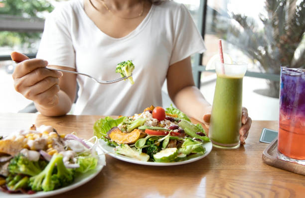 selektiver fokus der frau mit brokkoli und salat, die sie ein intermittierendes fasten mit einem gesunden essen von salat und entgiftung getränk,healthy lifestyle konzept. - kohlenhydratarme diät stock-fotos und bilder
