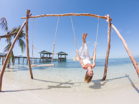 Beautiful woman on a swing on a paradise beach