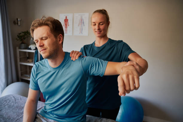 istock Young man suffering from hand injury doing stretching exercise with female physiotherapist 1278602360