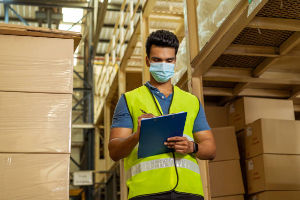 istock Young Indian factory warehouse worker wearing a protective face mask while working in logistic industry. 30s man checking item stock order during Covid 19 pandemic outbreak 1278603865