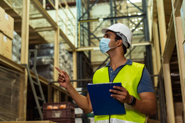 istock Young Indian factory warehouse worker wearing a protective face mask while working in logistic industry. 30s man checking item stock order during Covid 19 pandemic outbreak 1278603874