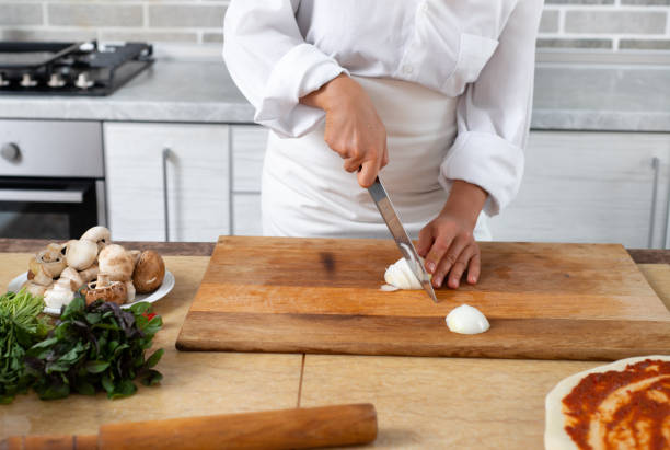 istock Close-up, the chef cuts the onion with a knife on a wooden board. Front view. 1278606439