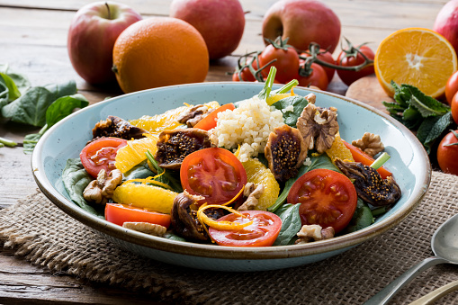 Colorful summer sweet salad with spinach, orange, cherry tomatoes, walnut, figs, quinoa, fresh fruit