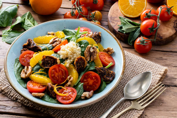 Colorful summer sweet salad with spinach, orange, cherry tomatoes, walnut, figs, quinoa, fresh fruit