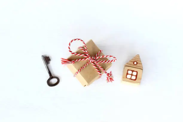 gift with a key and a house on a light surface top view