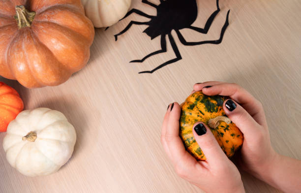 istock A man holds a small pumpkin in his hands. On the table are decorations for the celebration of Halloween. 1278609905
