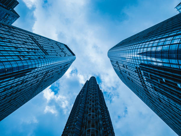 Three "Musketeers": A bottom-up view of high-rise office towers pointing to the sky in Shenzhen, China This photo was taken at a bottom-up view in the CBD area of Shenzhen, China. It focused on three skyscrapers pointing to the sky from different sides of the frame. They made up an image of three "musketeers" holding swords to the sky as a whole. shenzhen technology stock pictures, royalty-free photos & images
