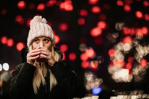 Festive night in the city Beautiful young blond woman enjoying mulled wine at Christmas market mulled wine photos stock pictures, royalty-free photos & images