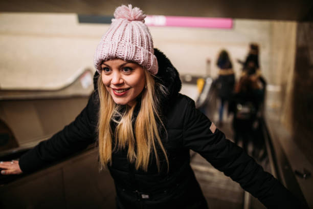 Beautiful young woman on subway escalator on cold winter night