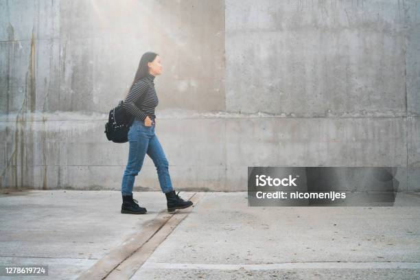 Asian Woman Walking Outdoors Against Grey Wall Stock Photo - Download Image Now - 18-19 Years, Adult, Beautiful People
