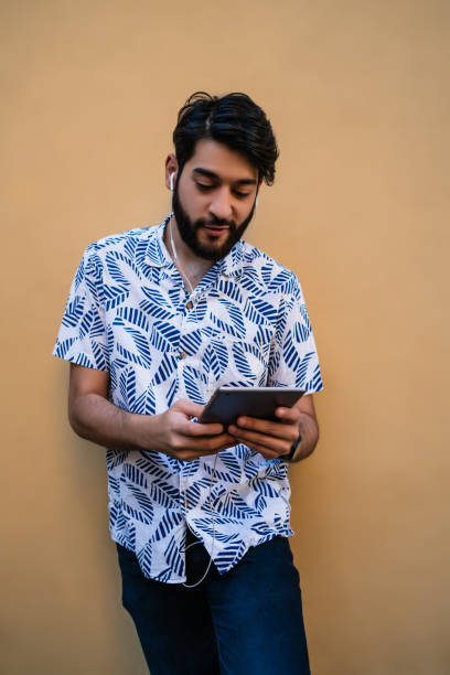 istock Latin man using his digital tablet with earphones. 1278619786
