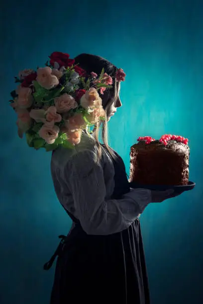 Vintage romantic girl holding chocolate cake with red curran berries and flowers in hair