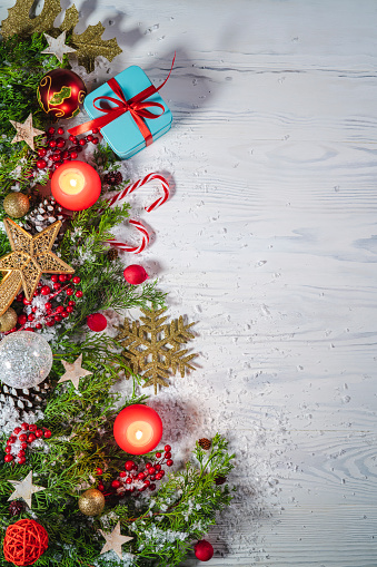 Christmas snow background on rustic wite wood background with candles, pine cones and branches, giftes and baubles