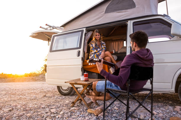 Couple with their camper van on a beach at sunset stock photo