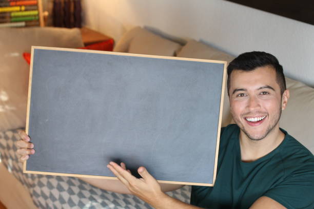 Young ethnic man holding blackboard.