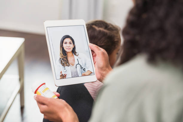 istock Daughter sits on floor while mom video conferences with doctor 1278631573