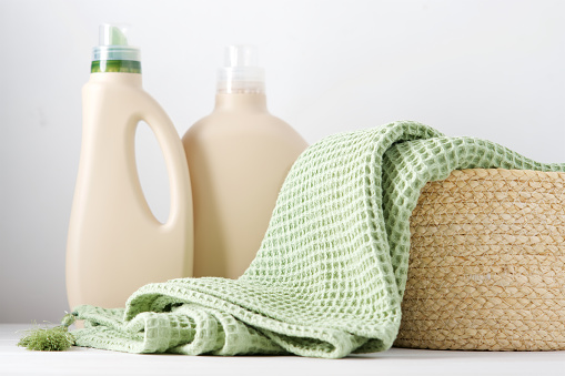 Manta limpia en cesta de mimbre blanco llena de botellas de mendigo de lavado ecológicas photo