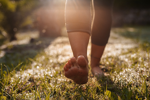 Young woman doing walk-meditation in her garden [model with a simple catalogue tattoo]