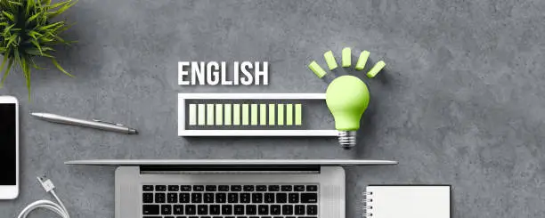 lightbulb and loading bar with the word ENGLISH and office equipment on concrete background